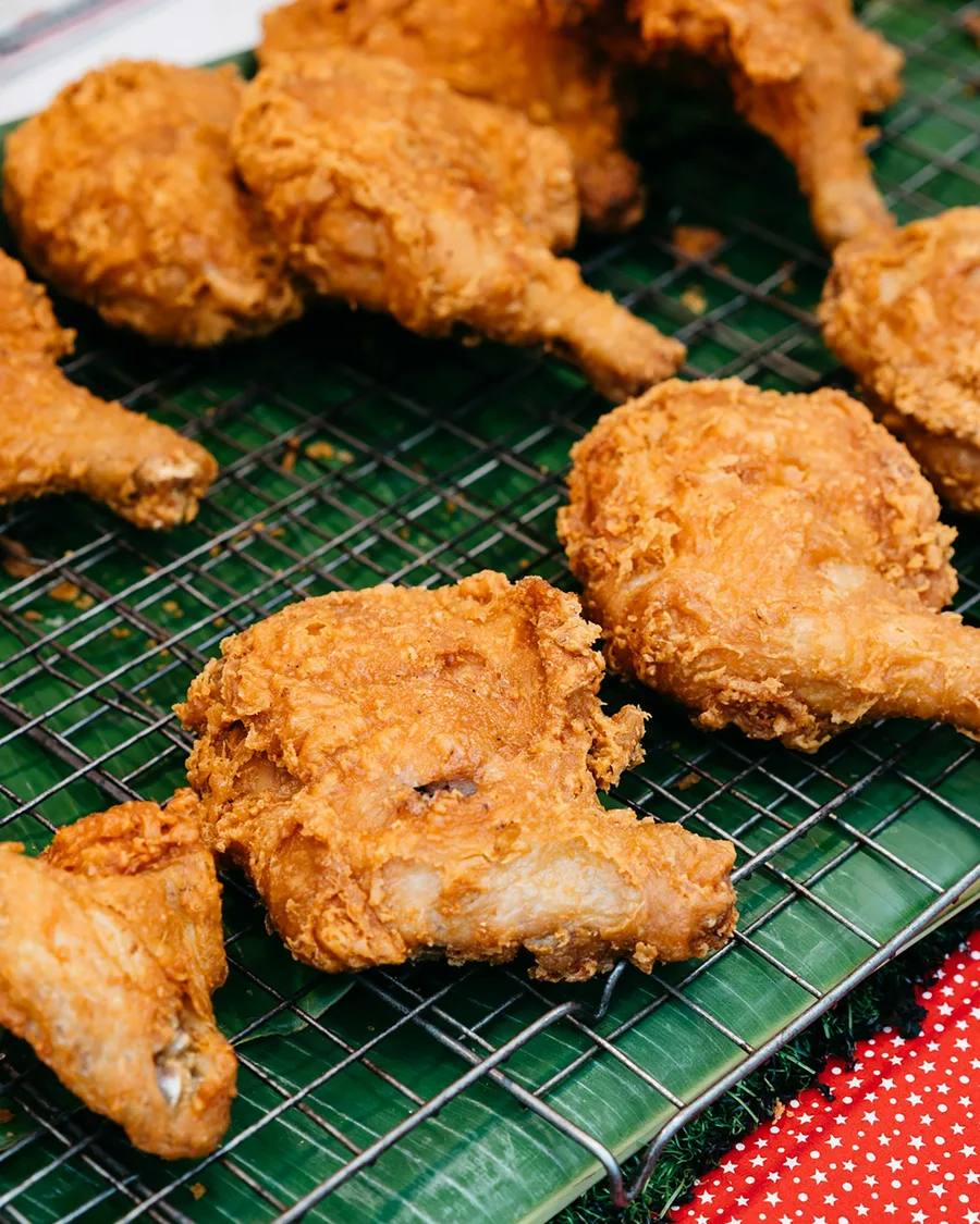 Pieces of fried chicken cooling on a wire rack.