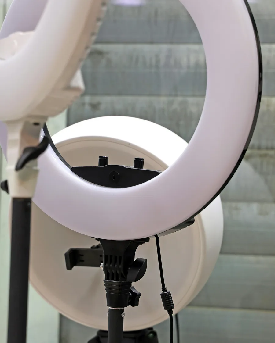 Two circular studio lights on stands beside a shuttered window.